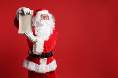 Photo of Merry Christmas. Santa Claus showing blank paper sheet on red background, space for text