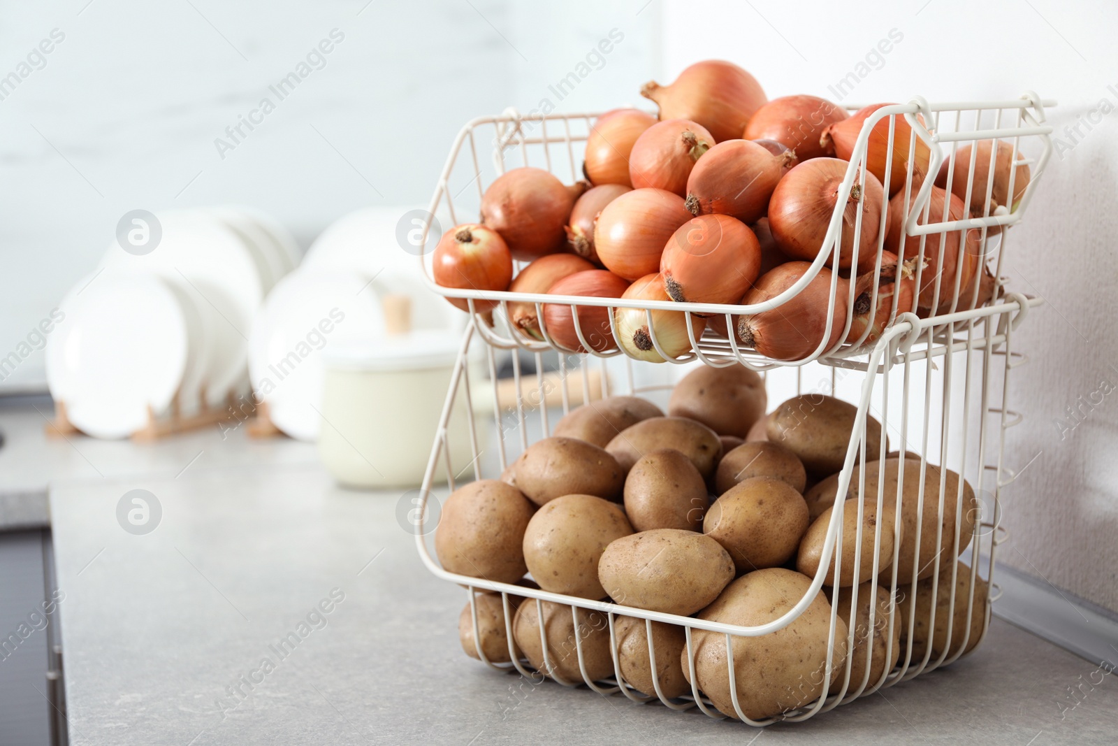 Photo of Container with potatoes and onions on grey kitchen counter, space for text. Orderly storage