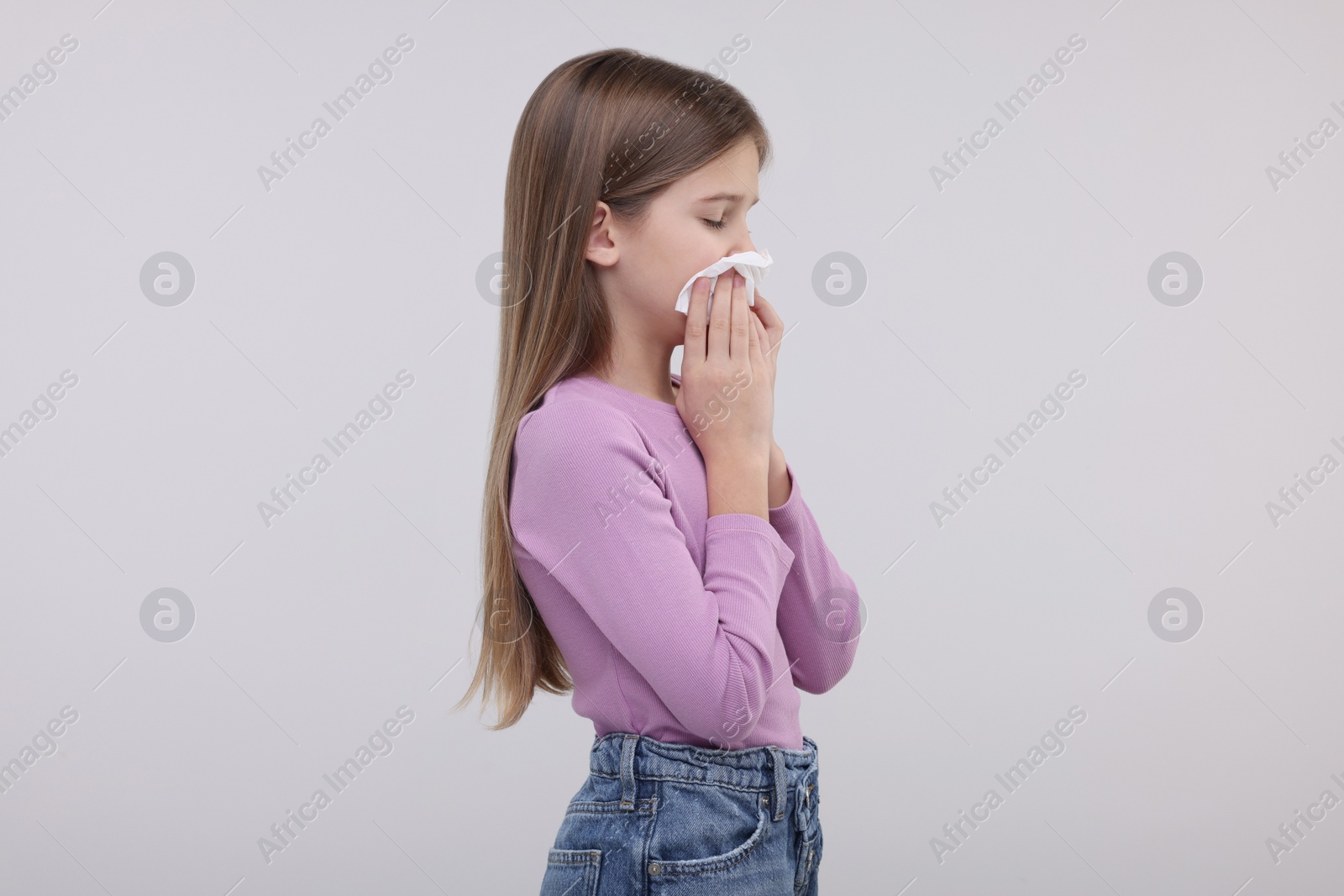 Photo of Sick girl with tissue coughing on light background