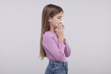 Sick girl with tissue coughing on light background