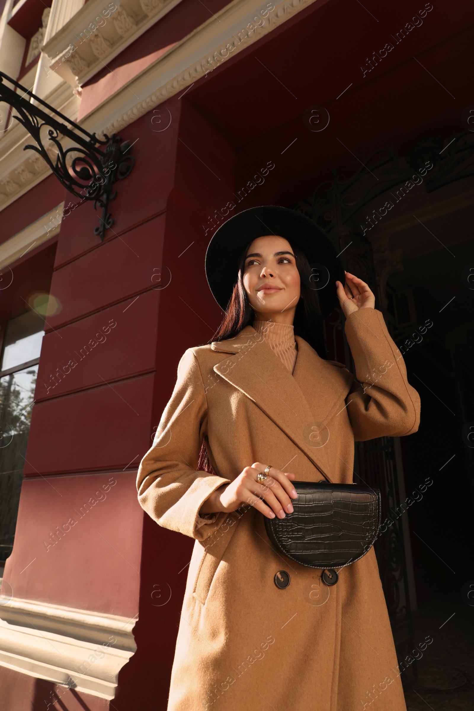 Photo of Beautiful young woman with stylish waist bag on city street, low angle view