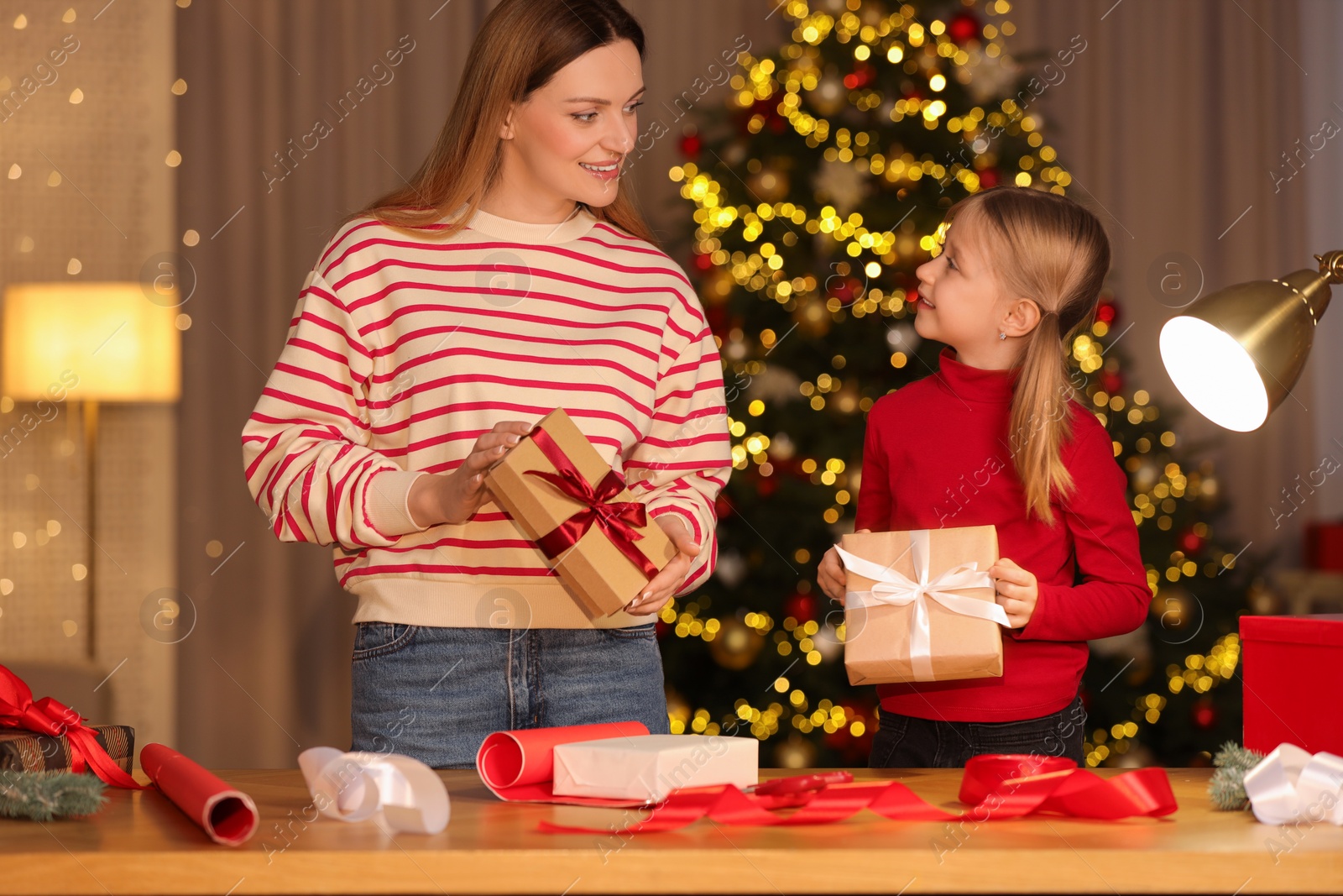Photo of Christmas presents wrapping. Mother and her little daughter holding gift boxes at home