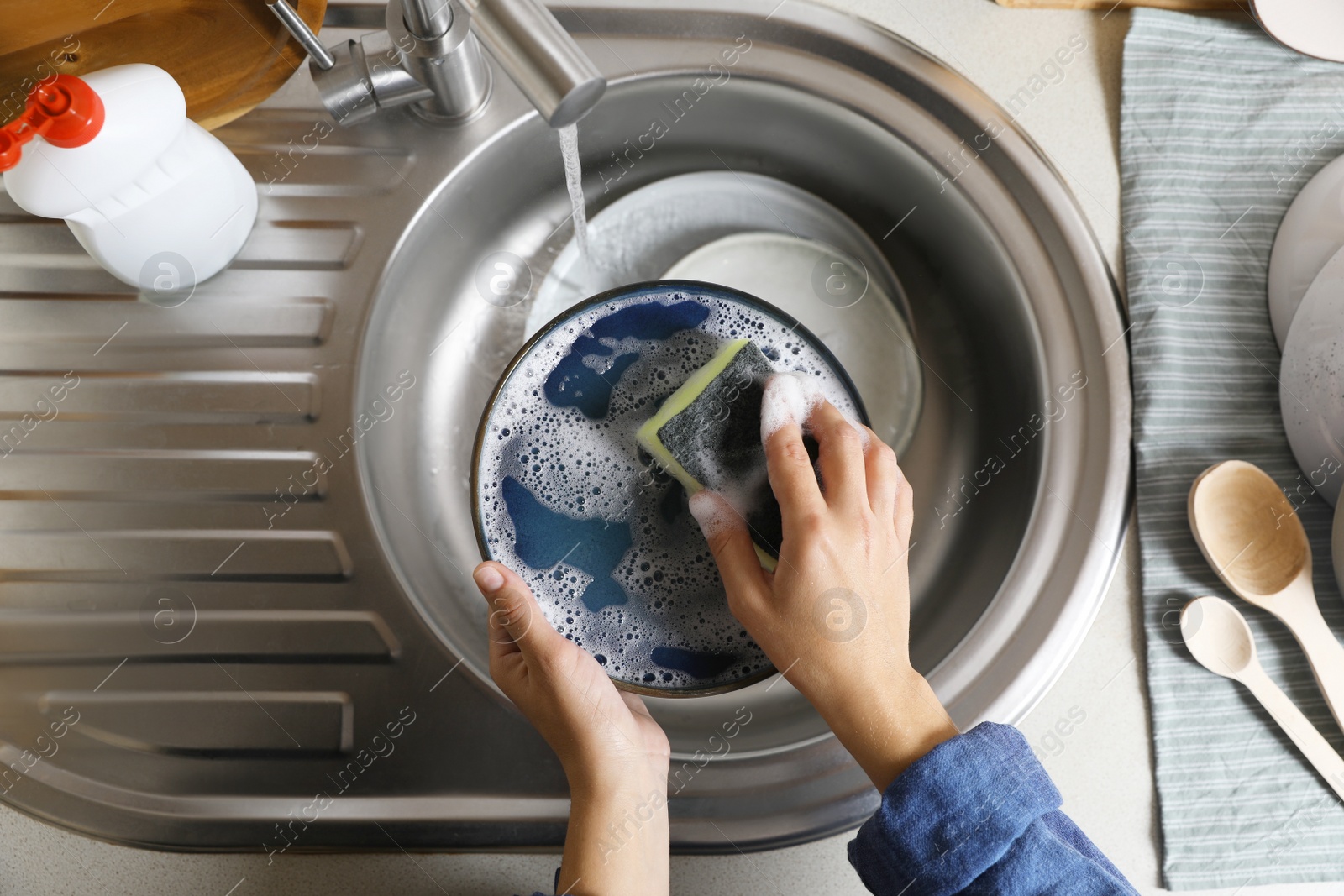 Photo of Woman washing plate in kitchen sink, above view