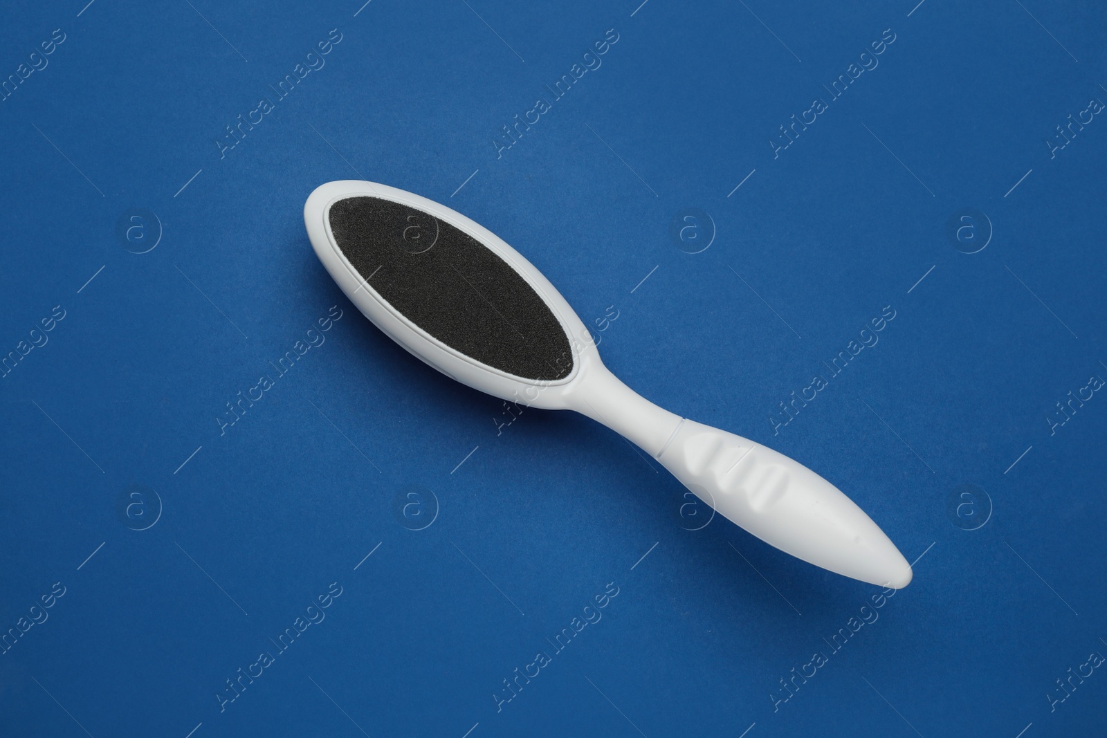Photo of White foot file on blue background, top view. Pedicure tool