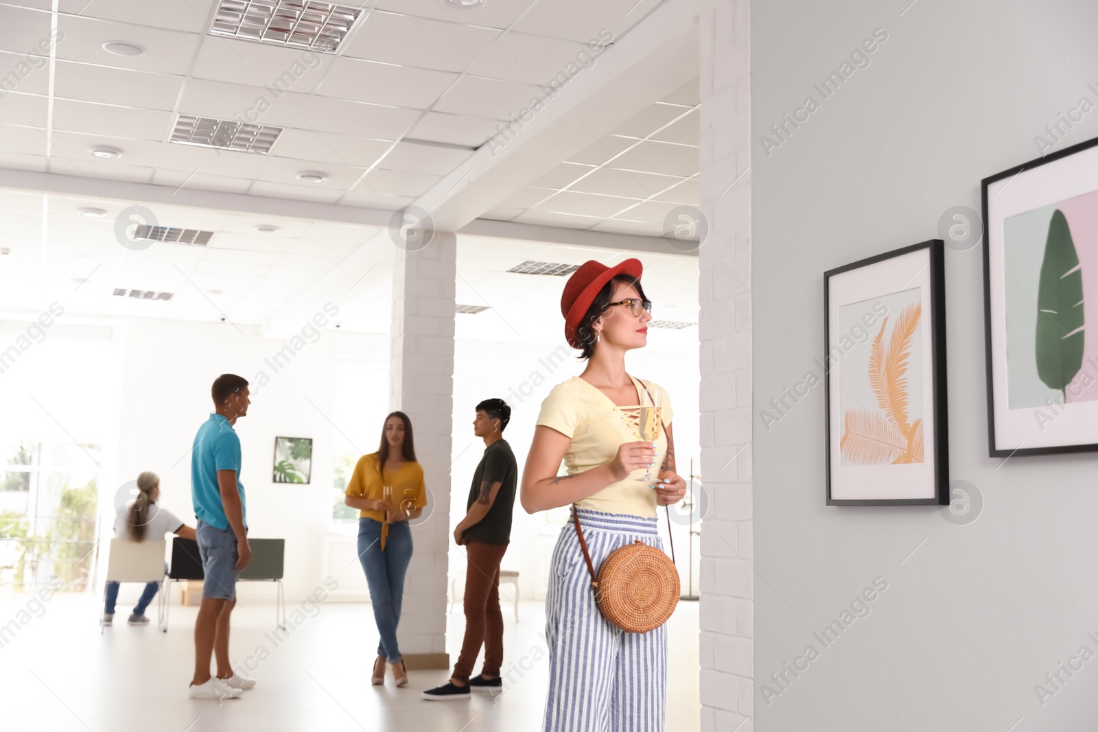 Photo of Young woman with glass of champagne at exhibition in art gallery