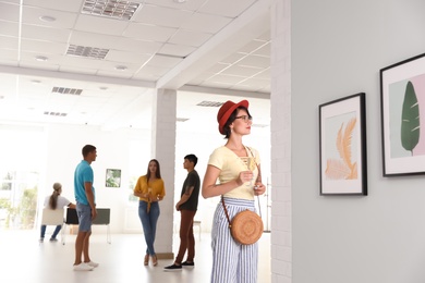 Young woman with glass of champagne at exhibition in art gallery