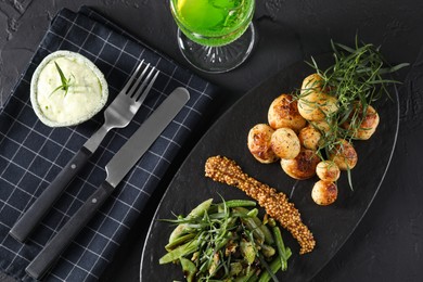 Photo of Delicious salad with tarragon, mustard and grilled potatoes served on black textured table, flat lay