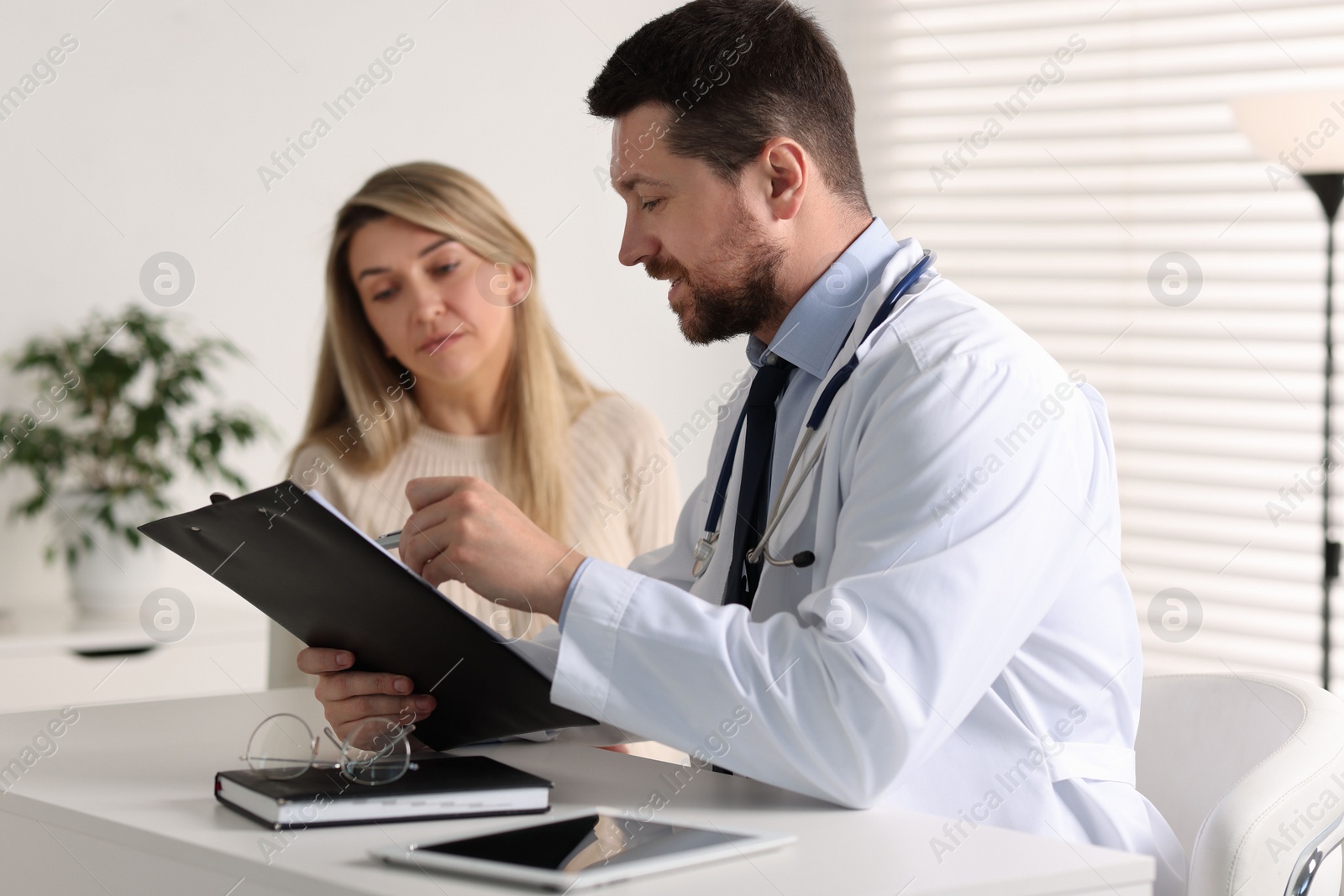 Photo of Professional doctor working with patient at white table in hospital