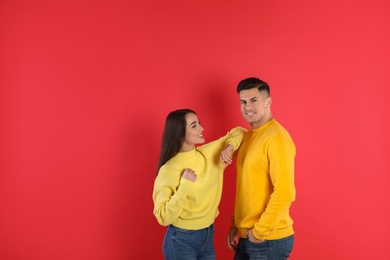 Photo of Happy couple wearing yellow warm sweaters on red background