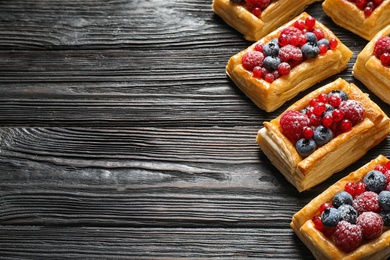 Fresh delicious puff pastry with sweet berries on dark wooden table. Space for text