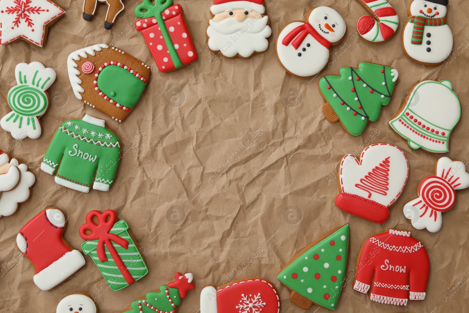 Photo of Frame made with different Christmas gingerbread cookies on crumpled parchment, top view. Space for text