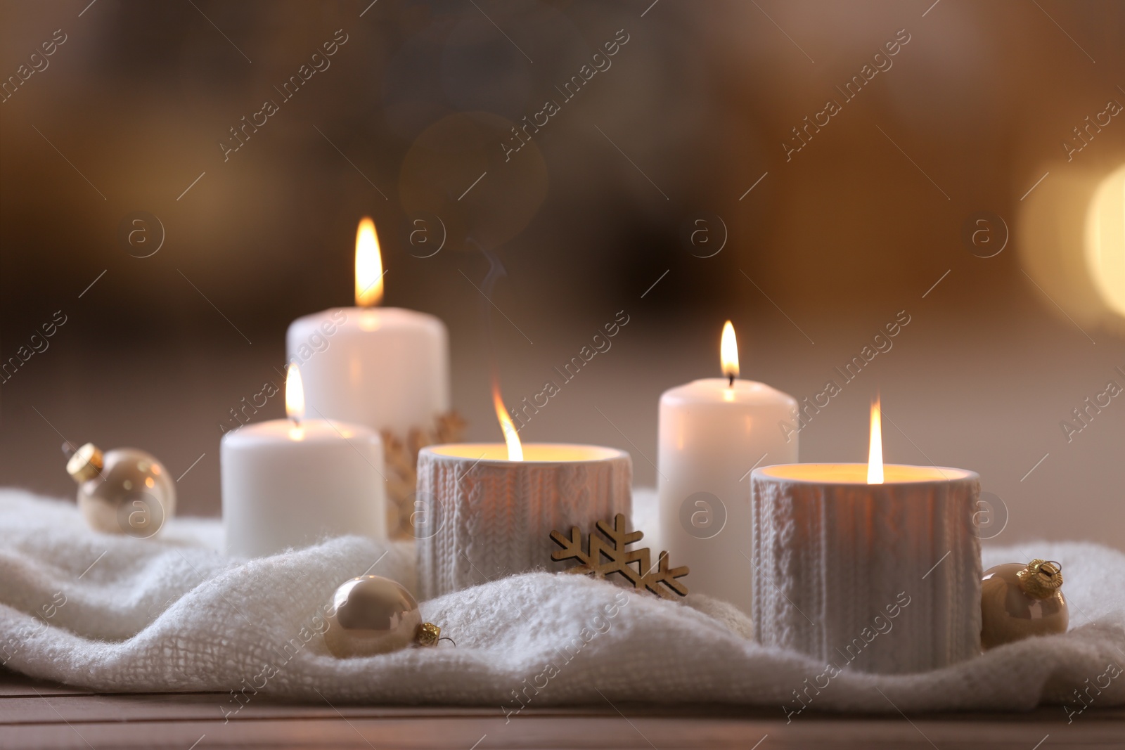 Photo of Composition with candles in ornate holder on wooden table against blurred background. Christmas decoration