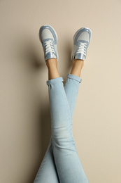 Woman wearing sneakers on beige background, closeup