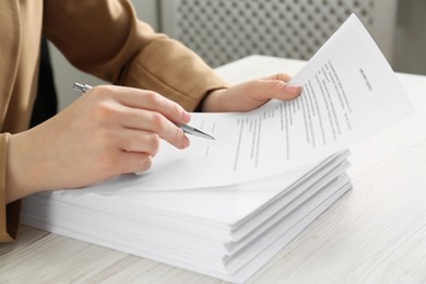 Woman signing document at wooden table, closeup