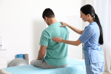 Photo of Orthopedist examining man's back in clinic. Scoliosis treatment