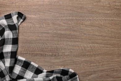 Photo of Checkered tablecloth on wooden table, top view. Space for text