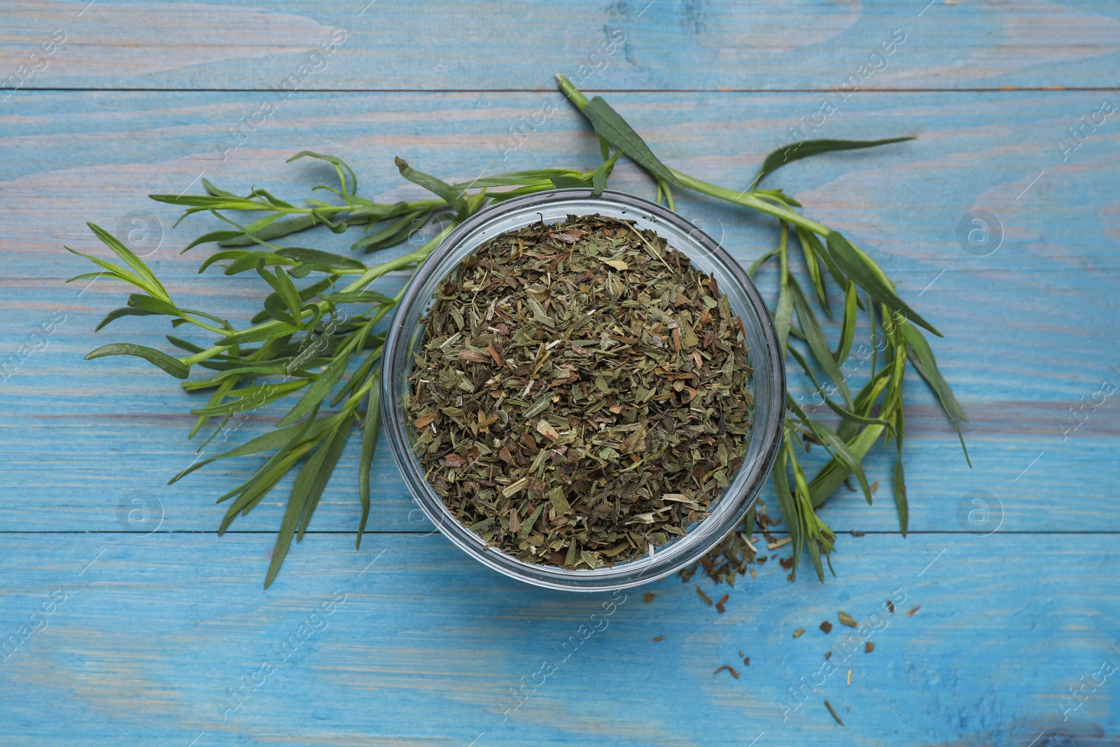 Photo of Dry and fresh tarragon on light blue wooden table, flat lay