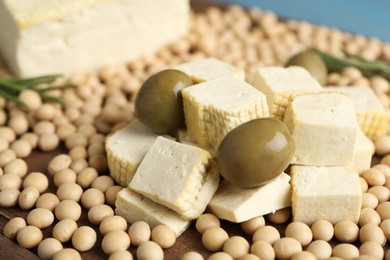 Cut tofu, olives and soya beans on wooden board, closeup