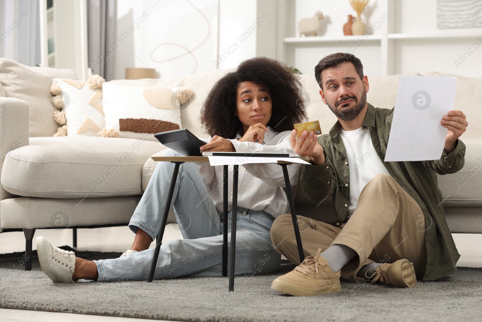 Photo of Confused couple with calculator, credit card and debt notification planning budget at home. Financial problem