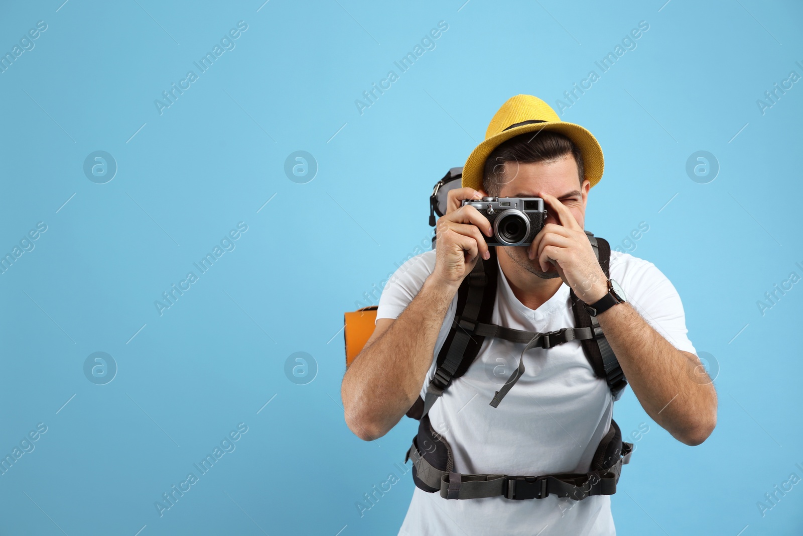 Photo of Male tourist with travel backpack taking picture on turquoise background, space for text