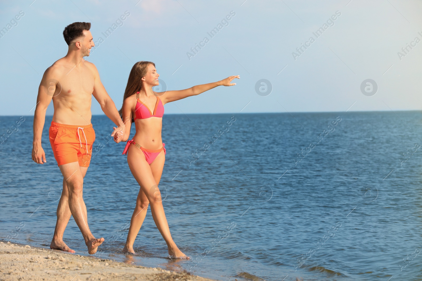 Photo of Young woman in bikini spending time with her boyfriend on beach. Lovely couple