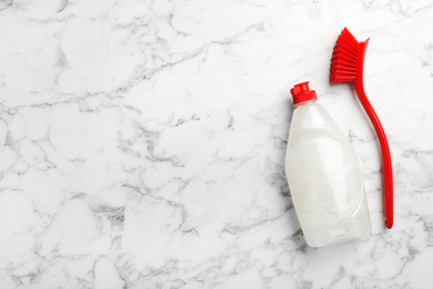 Photo of Cleaning product and brush for dish washing on marble background with space for text, top view