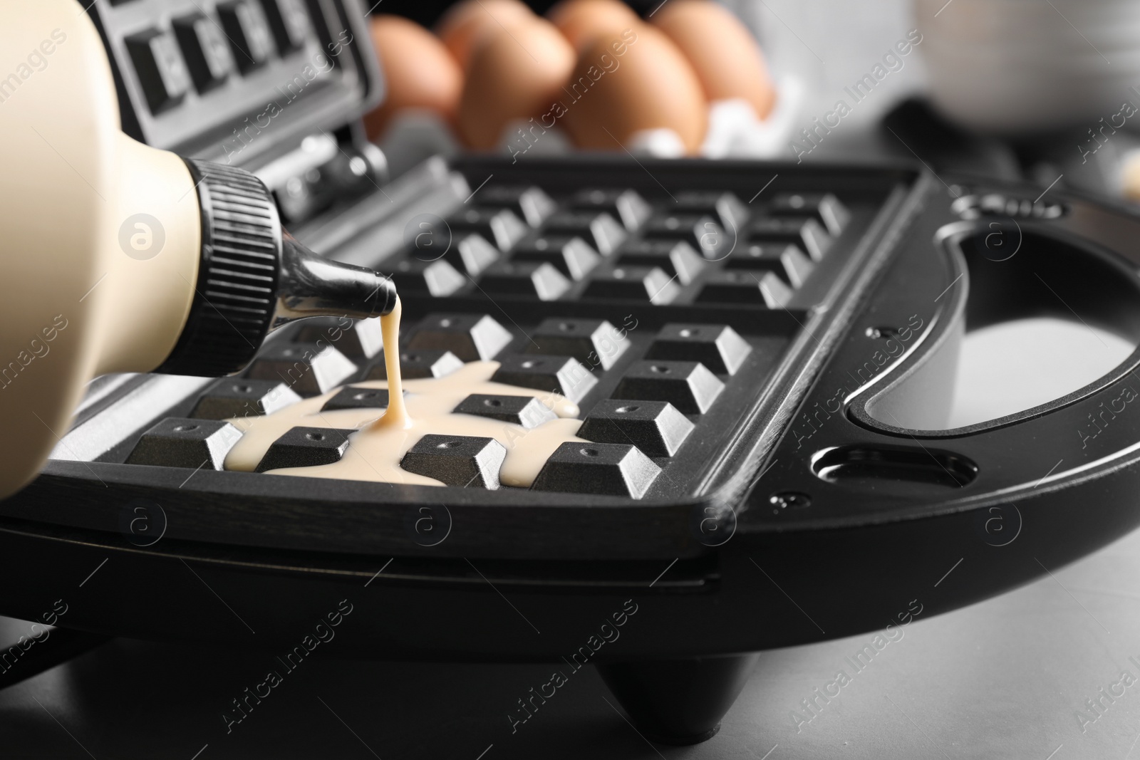 Photo of Pouring dough onto Belgian waffle maker, closeup