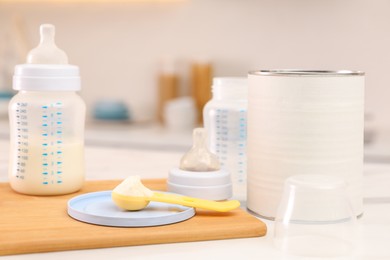 Photo of Feeding bottle with infant formula and powder on white table indoors