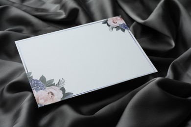 Photo of Blank invitation card on black fabric, closeup