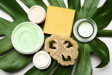 Composition with body care products, wisp and green leaf on white background, top view