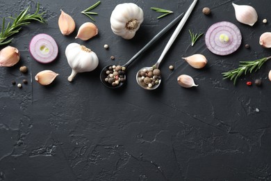 Photo of Fresh raw garlic, onion rings and spices on black table, flat lay. Space for text