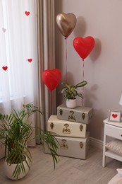 Photo of Cozy room interior with heart shaped balloons and storage trunks near window. Valentine Day celebration