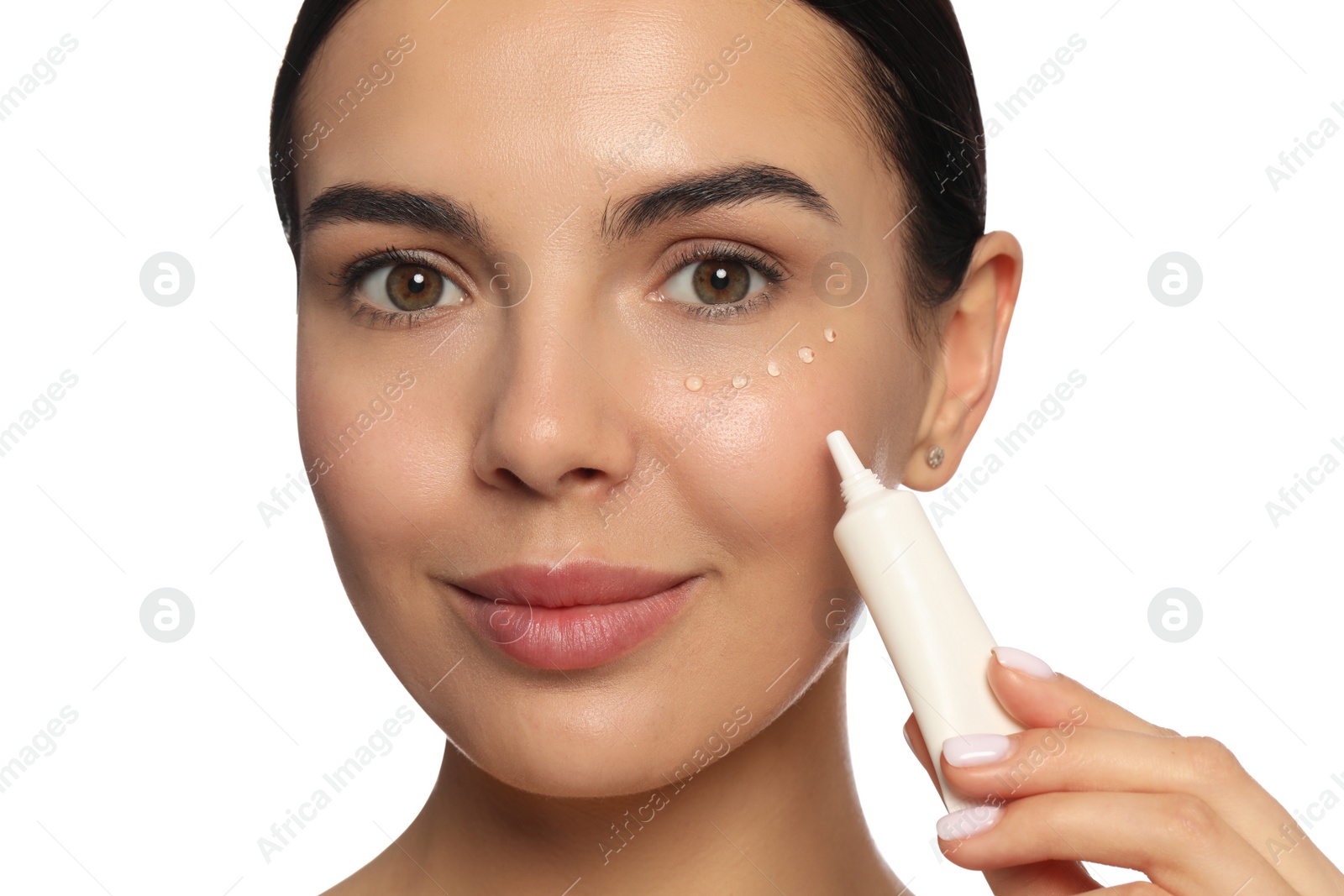 Photo of Beautiful young woman applying gel on skin under eye against white background