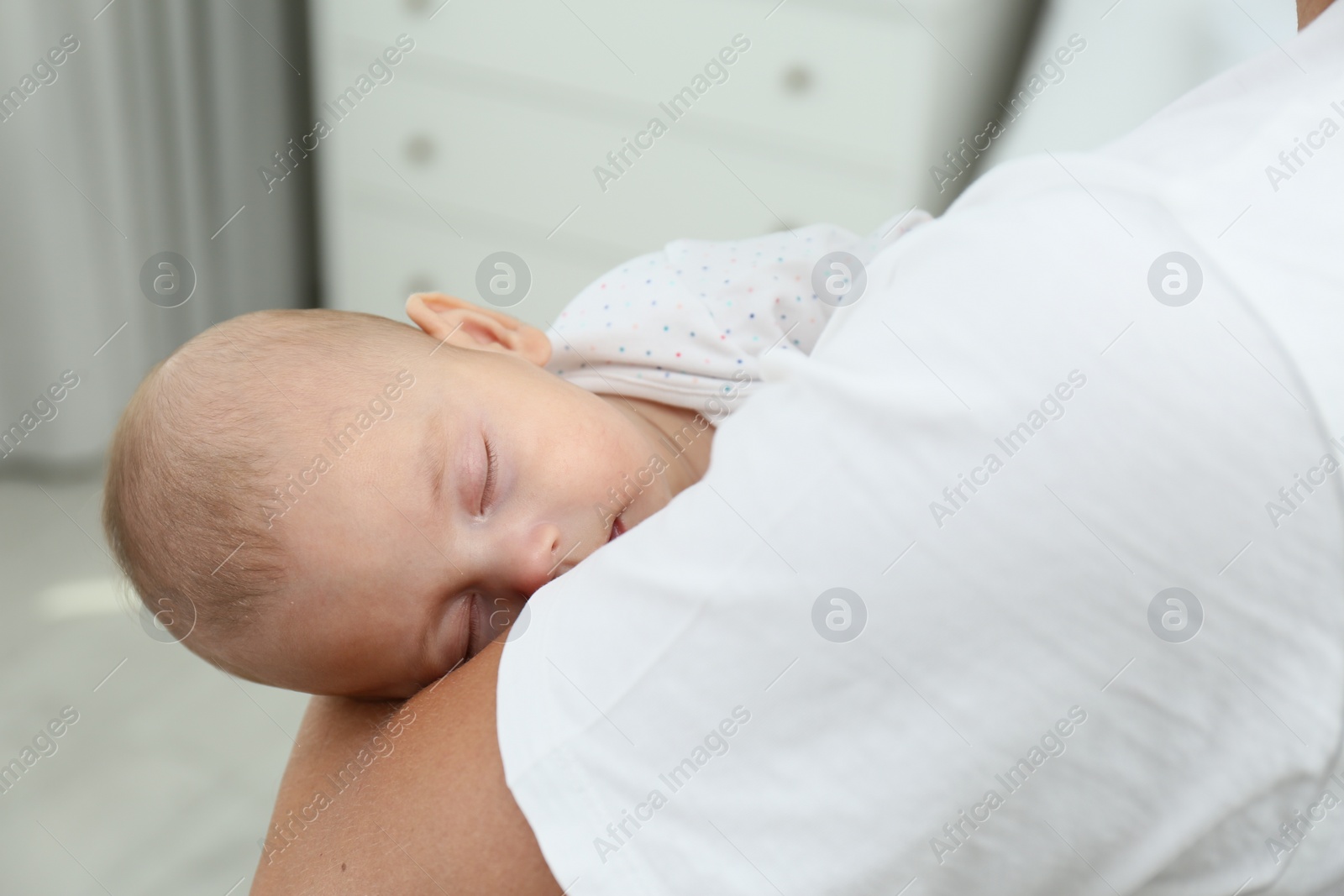 Photo of Father holding his cute sleeping baby at home, closeup