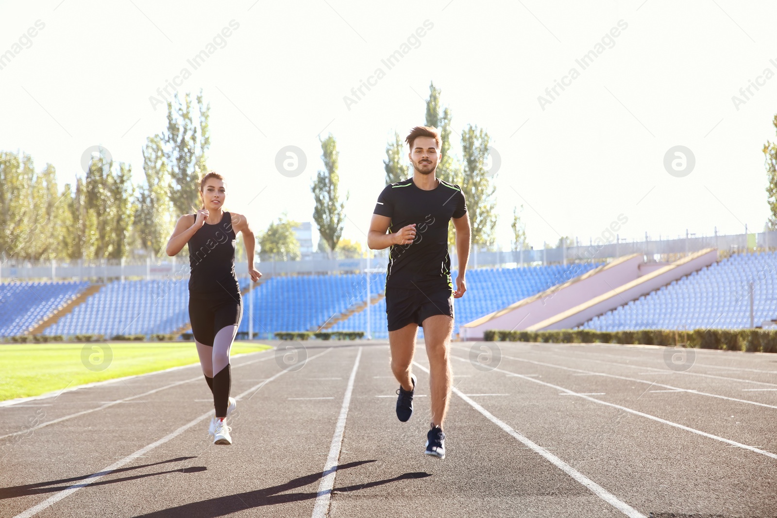 Photo of Sporty couple running at stadium on sunny morning