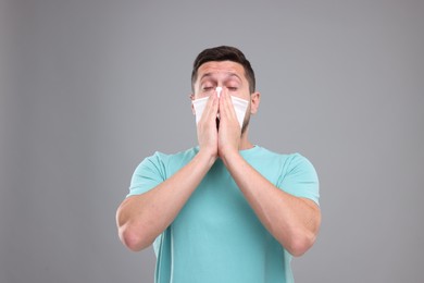 Allergy symptom. Man sneezing on light grey background