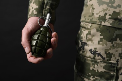 Photo of Soldier holding hand grenade on black background, closeup. Military service
