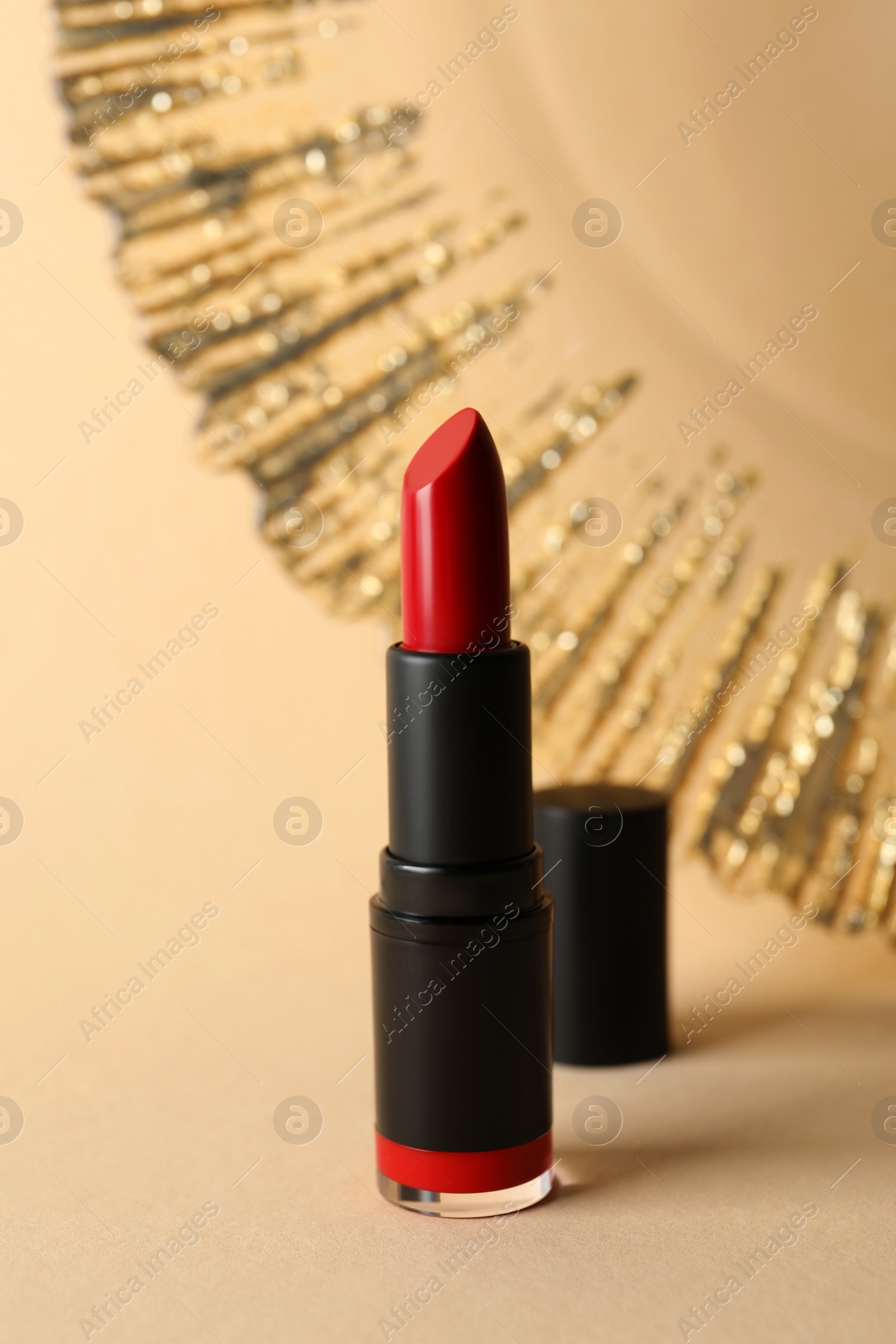 Photo of Beautiful glossy red lipstick on beige background