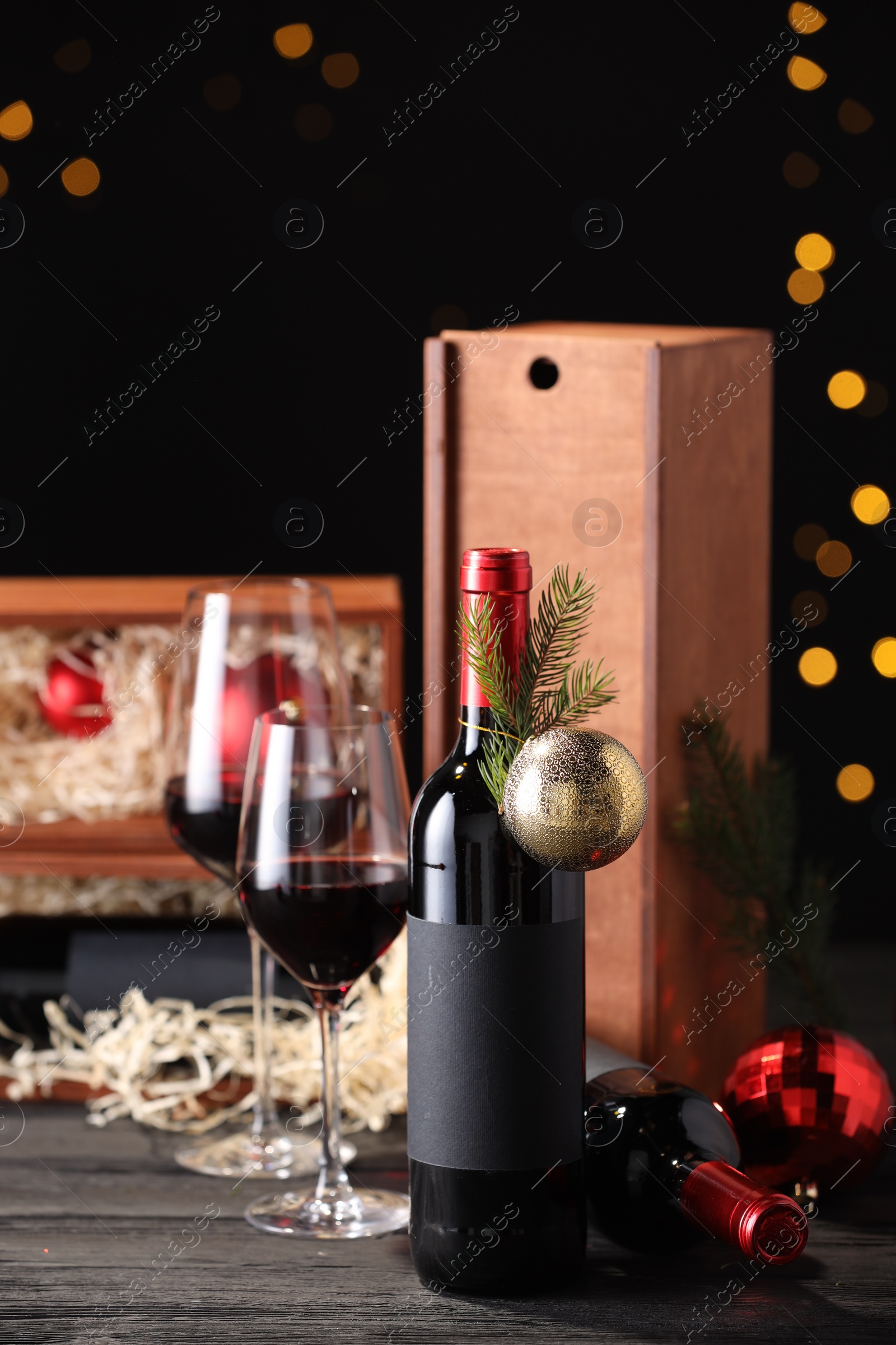 Photo of Bottles of wine, glasses, wooden boxes, fir twigs and Christmas balls on table