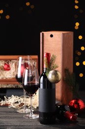 Bottles of wine, glasses, wooden boxes, fir twigs and Christmas balls on table