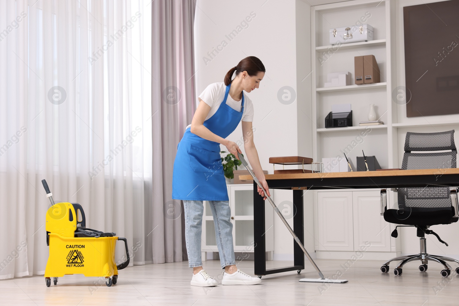 Photo of Cleaning service. Woman washing floor with mop in office