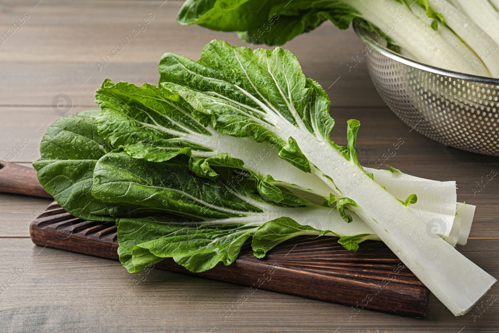 Photo of Leaves of fresh green pak choy cabbage with water drops on wooden table