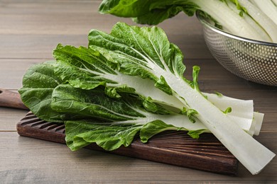 Photo of Leaves of fresh green pak choy cabbage with water drops on wooden table