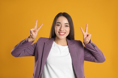 Photo of Woman in violet blazer showing number four with her hands on yellow background