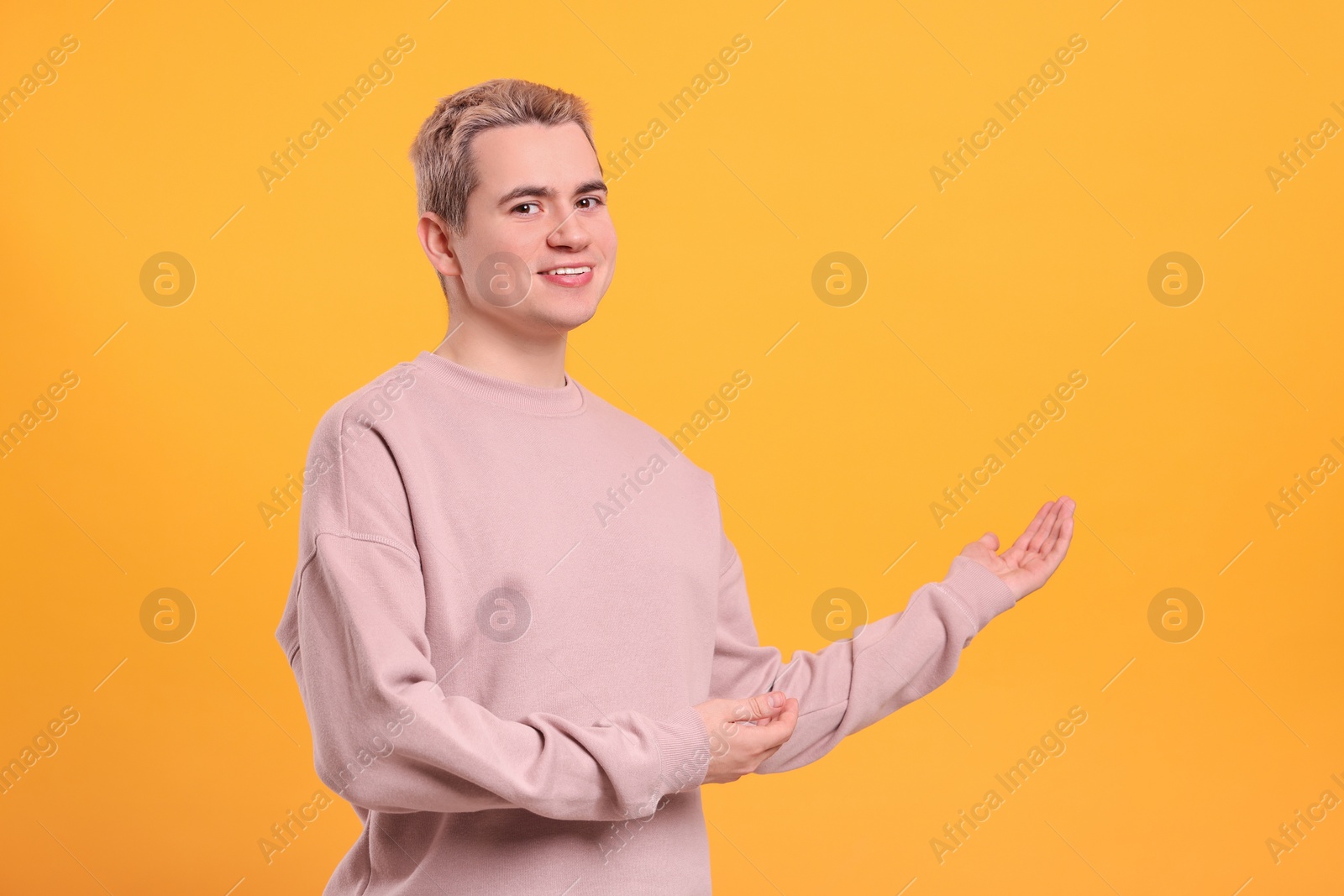 Photo of Happy man inviting to come in against orange background