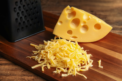 Tasty grated and whole cheese on wooden table