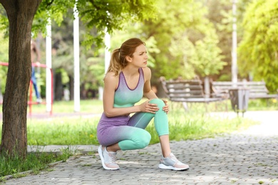 Photo of Young woman suffering from knee pain in park