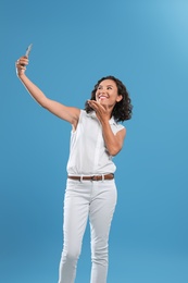 Photo of Happy young woman taking selfie on blue background