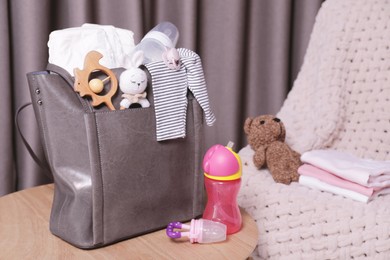 Photo of Mother's bag with baby's stuff on wooden table indoors