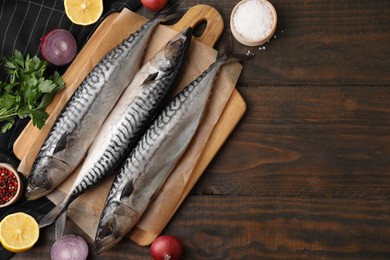 Photo of Tasty salted mackerels and products on wooden table, flat lay. Space for text